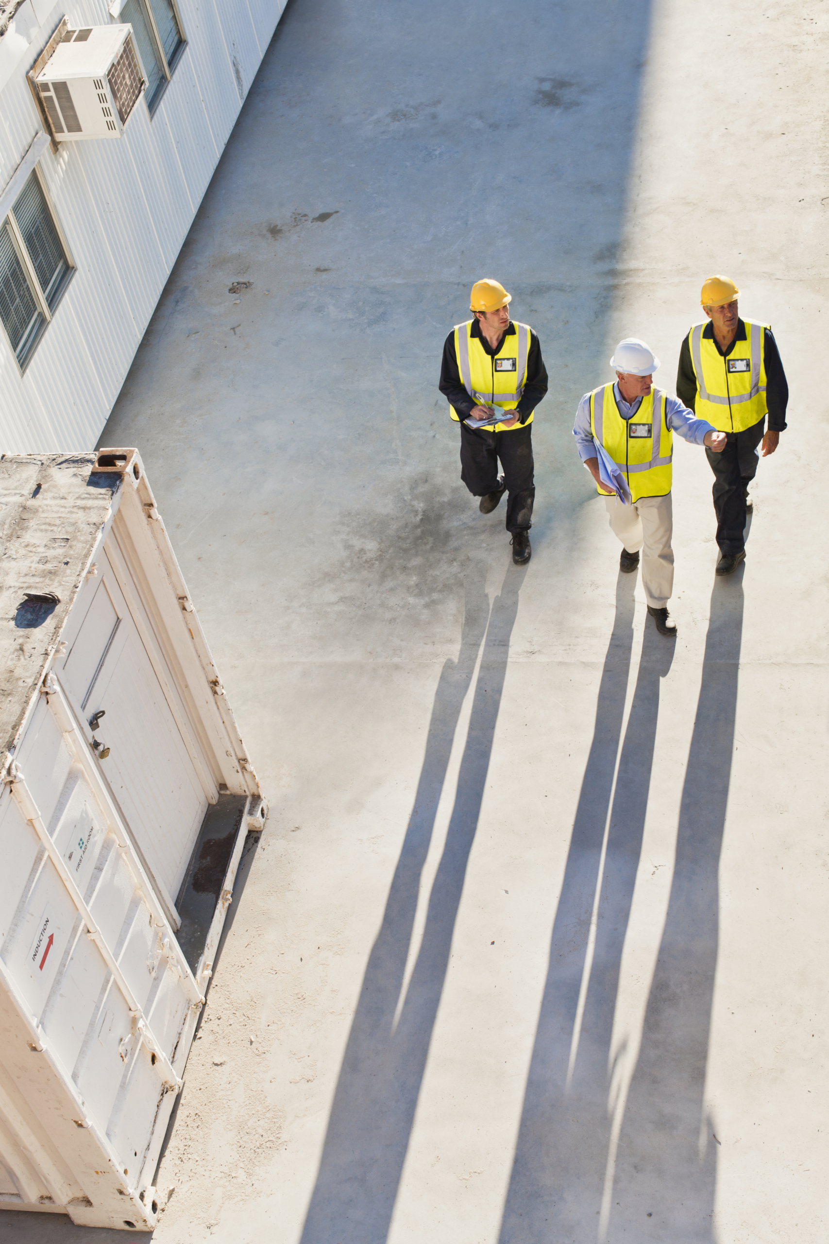 Three engineers with safety hats walking through a construction site
