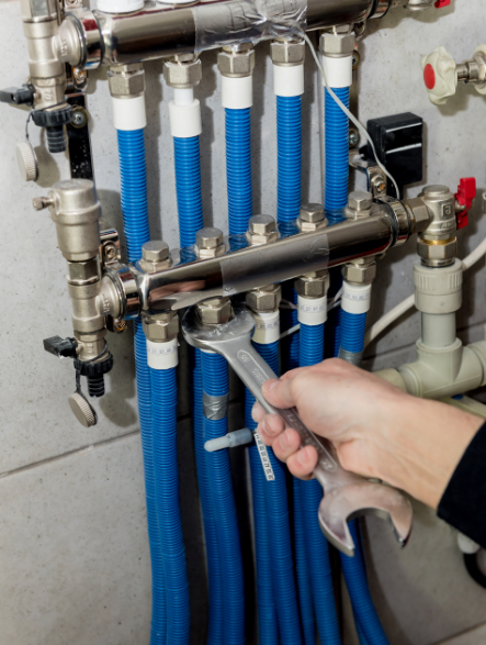 Engineer using a spanner on a central heating manifold